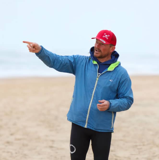 Charly Henno, casquette rouge, désigne un point à l'horizon en expliquant la lecture du spot