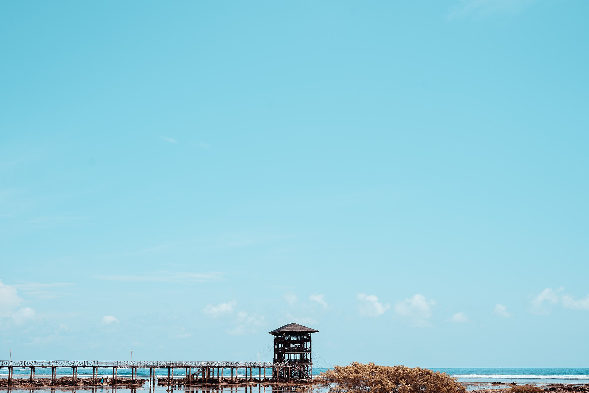 La tour d'observation de Cloud 9 au bout de son ponton de bois, sur le récif de Siargao à marée basse, sous un grand ciel bleu